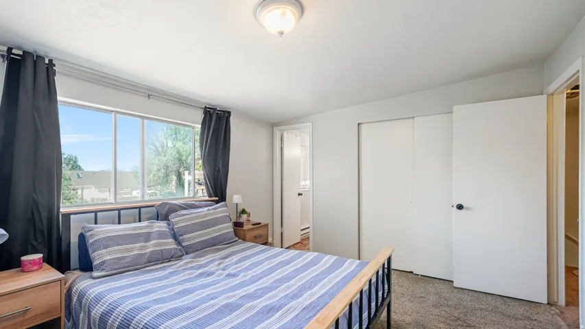 Bedroom featuring a wide window, neutral wall paint, ceiling light fixture, and double-door closet