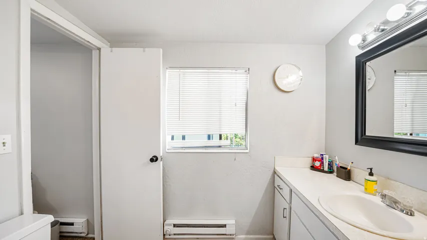 Bathroom featuring a single vanity with an integrated sink, a rectangular mirror with a black frame, and a wall-mounted light fixture