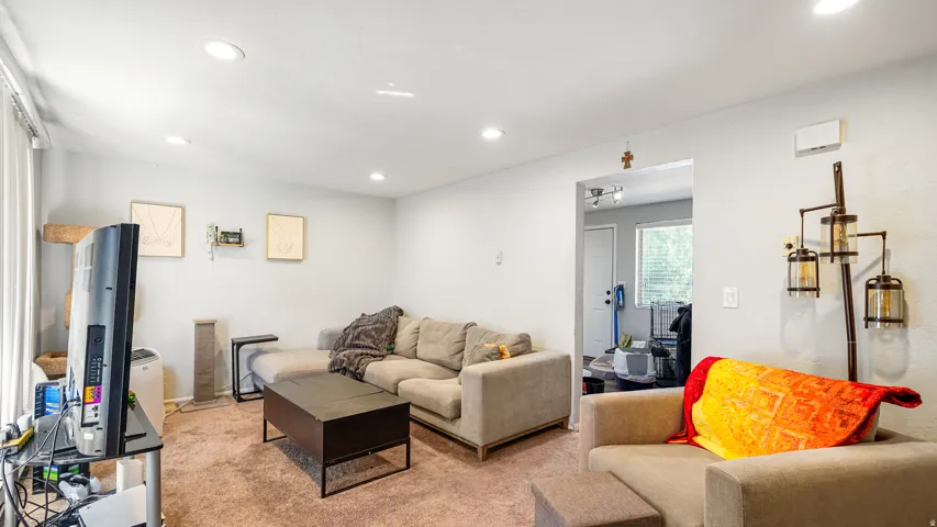 Living area featuring recessed lighting, light-colored walls, and a textured carpeted floor