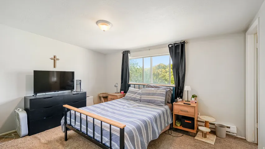 Bedroom featuring a large window, neutral wall paint, and textured carpeting