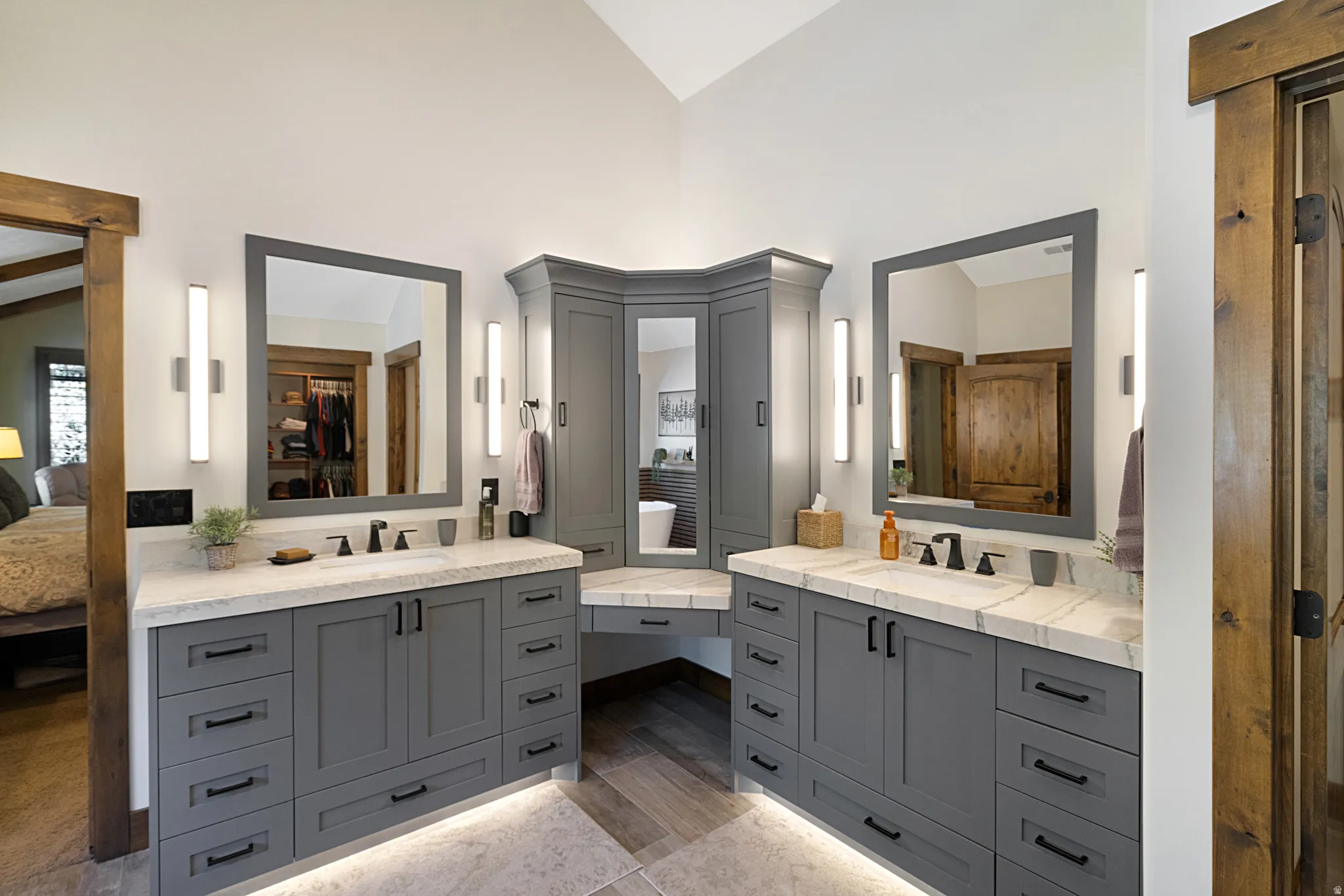 Beautiful bathroom featuring gray cabinetry with matte black hardware, stone countertops, and under-cabinet lighting