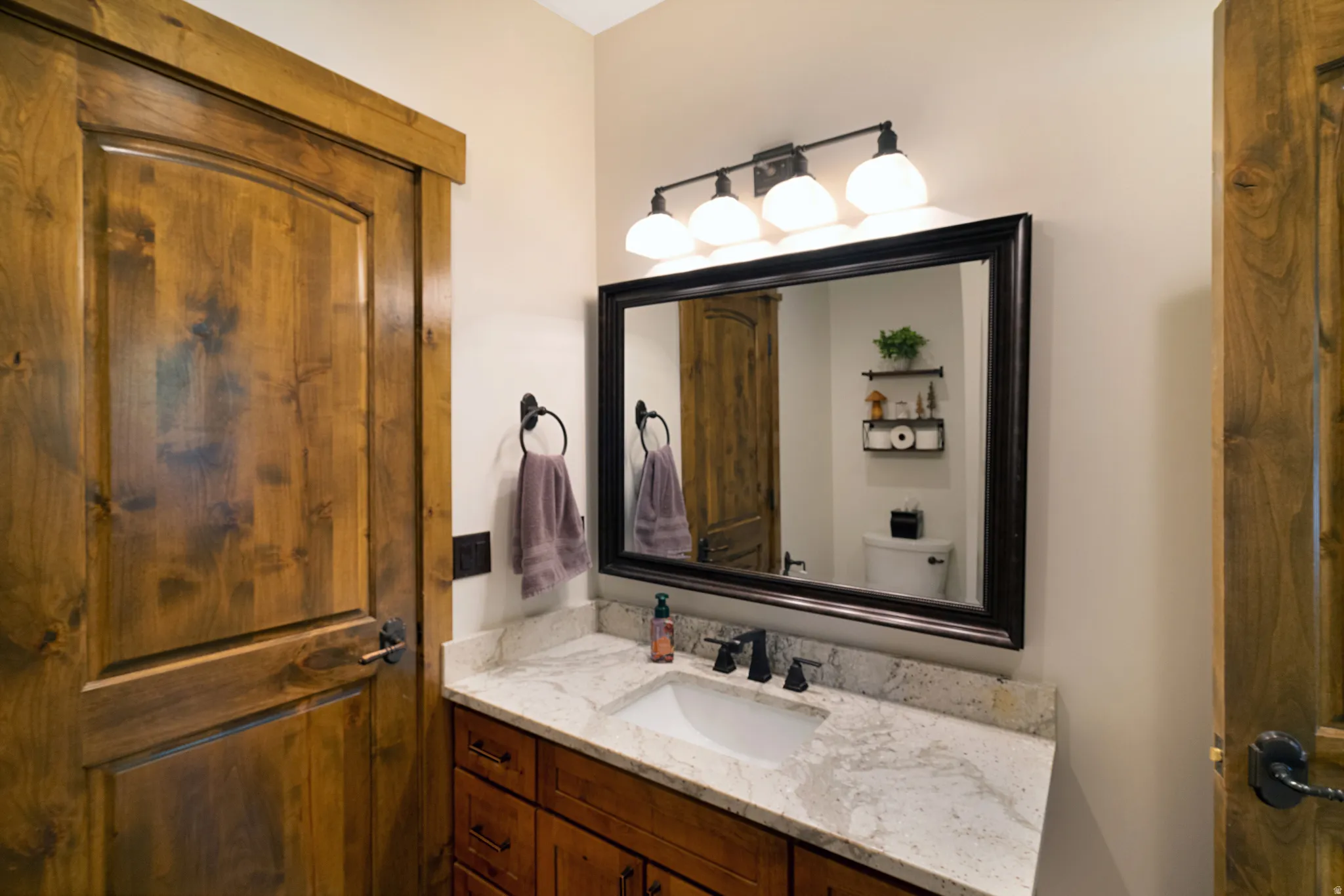 Bathroom vanity featuring a light-toned countertop, undermount sink, and dark-finished faucet