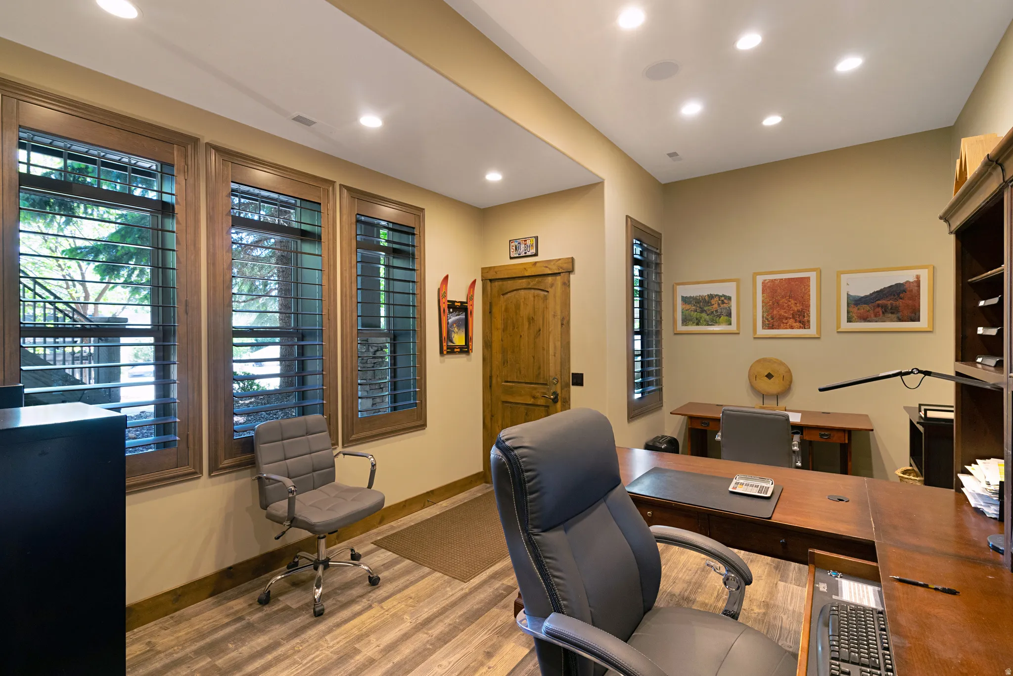 Dedicated workspace featuring wood-finish flooring, recessed lighting, and a solid wood door