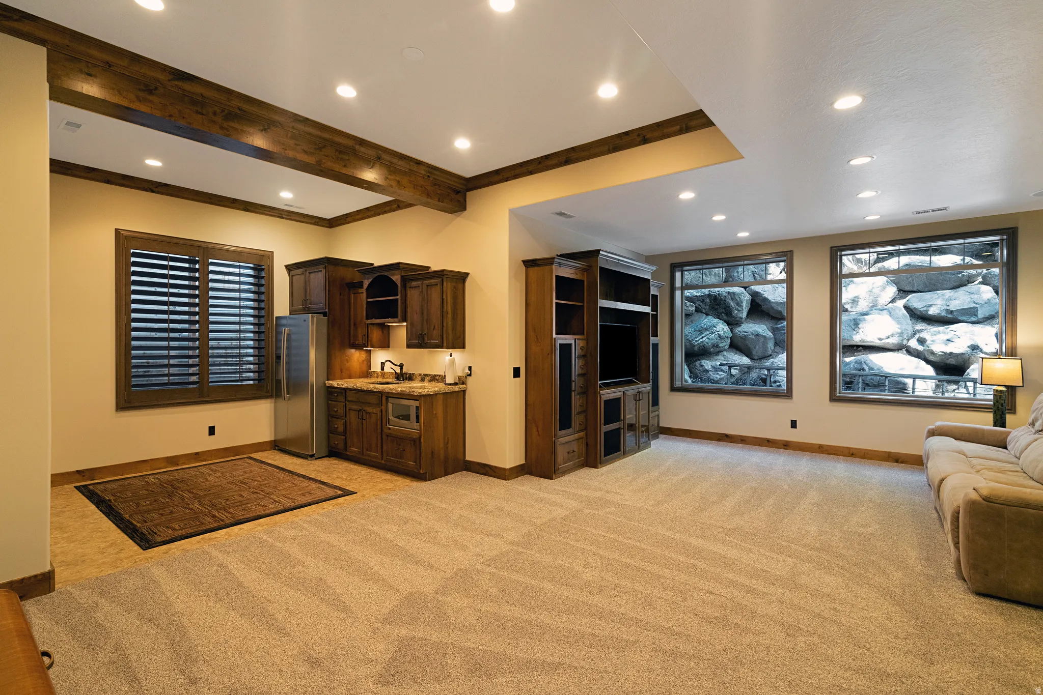 Finished lower level featuring a built-in wet bar with wood cabinetry and a stainless steel refrigerator