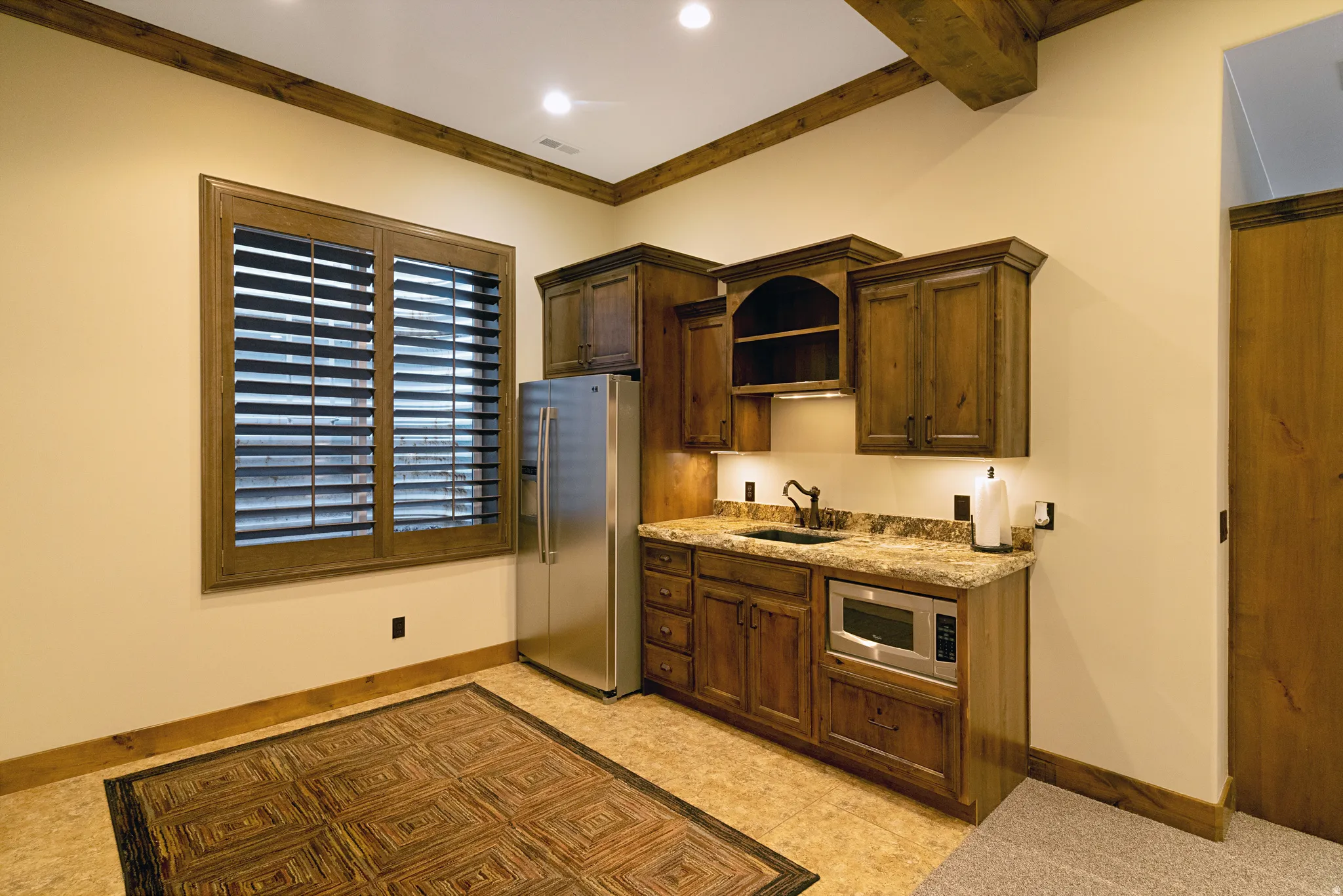 Wet bar featuring a compact refrigerator, built-in microwave, and undermount sink