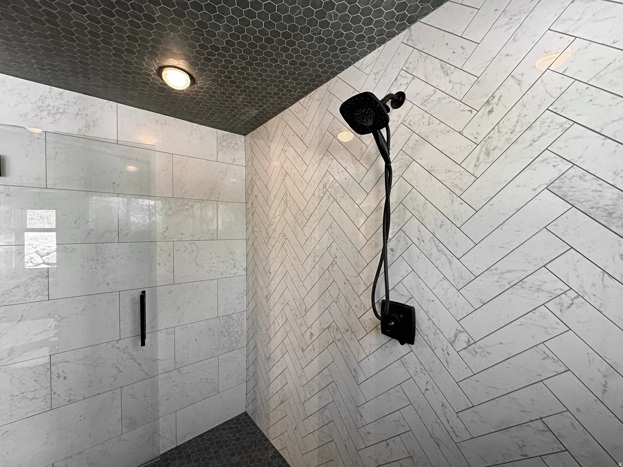 Walk-in shower featuring a fixed glass panel and matte black hardware