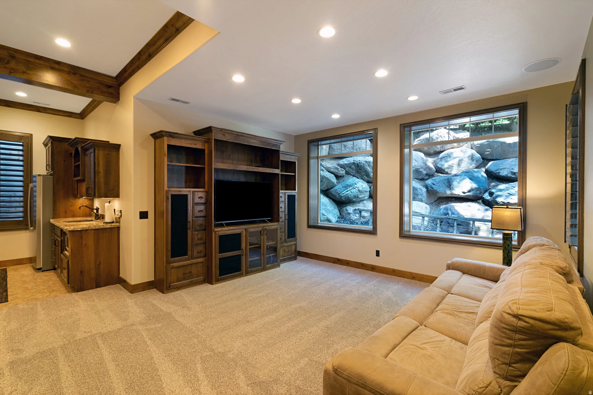 Spacious room featuring a built-in entertainment center, recessed lighting, and a wet bar with a stainless steel refrigerator