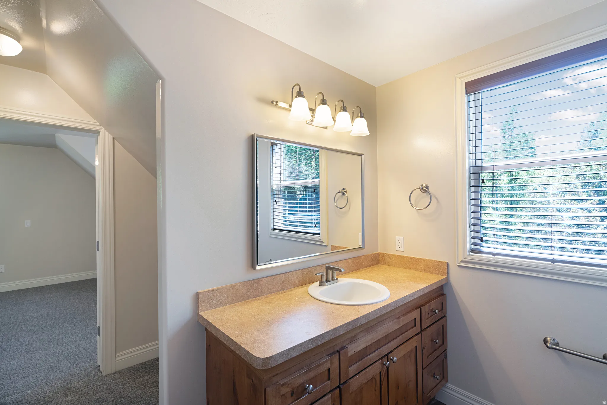 Bathroom vanity featuring a light-toned countertop with an integrated sink, brushed nickel faucet, and wood-finish cabinetry with multiple drawers and cabinet storage