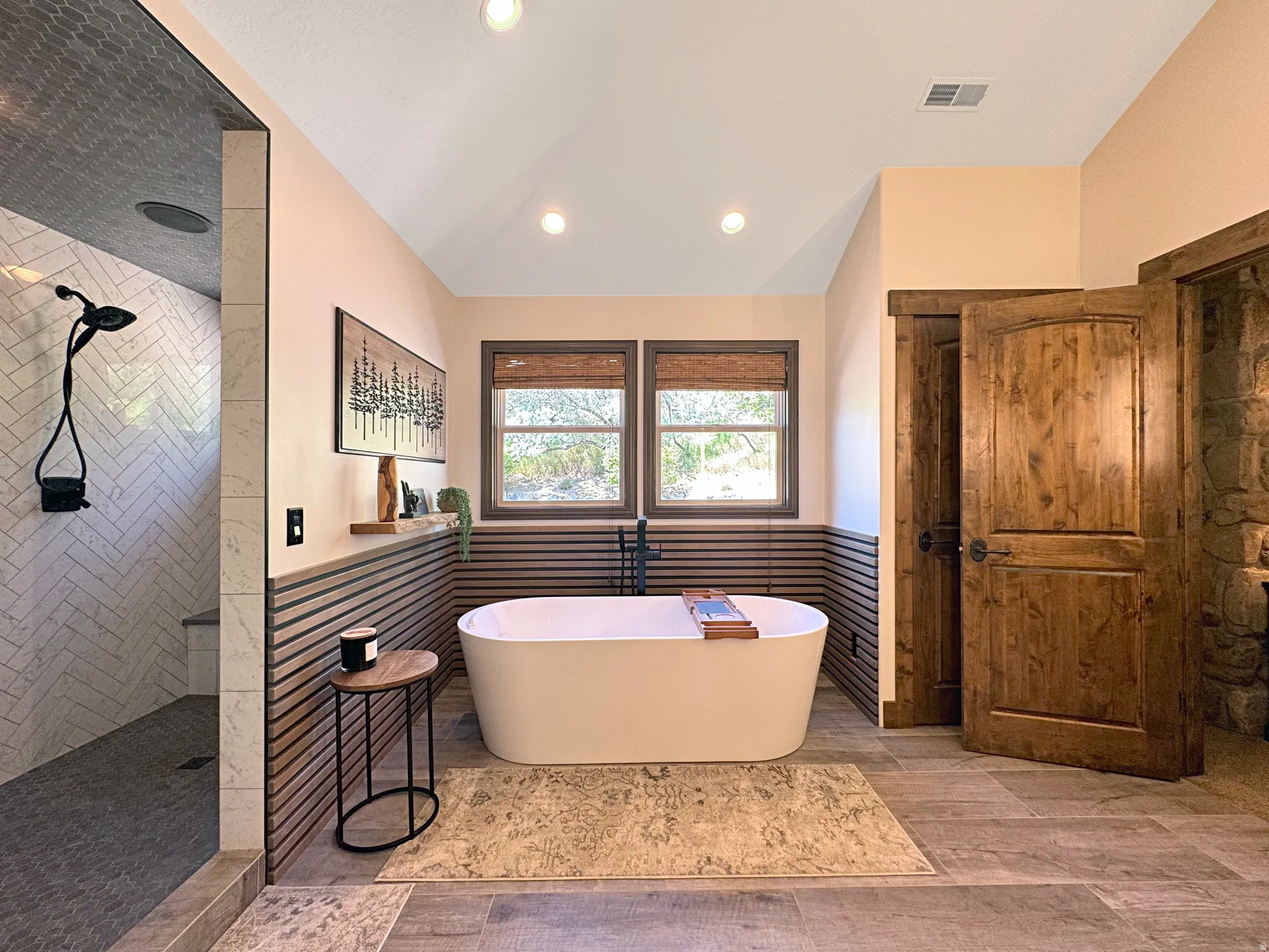 Freestanding soaking tub with a wall-mounted faucet, complemented by wood-finish wall paneling and two large windows
