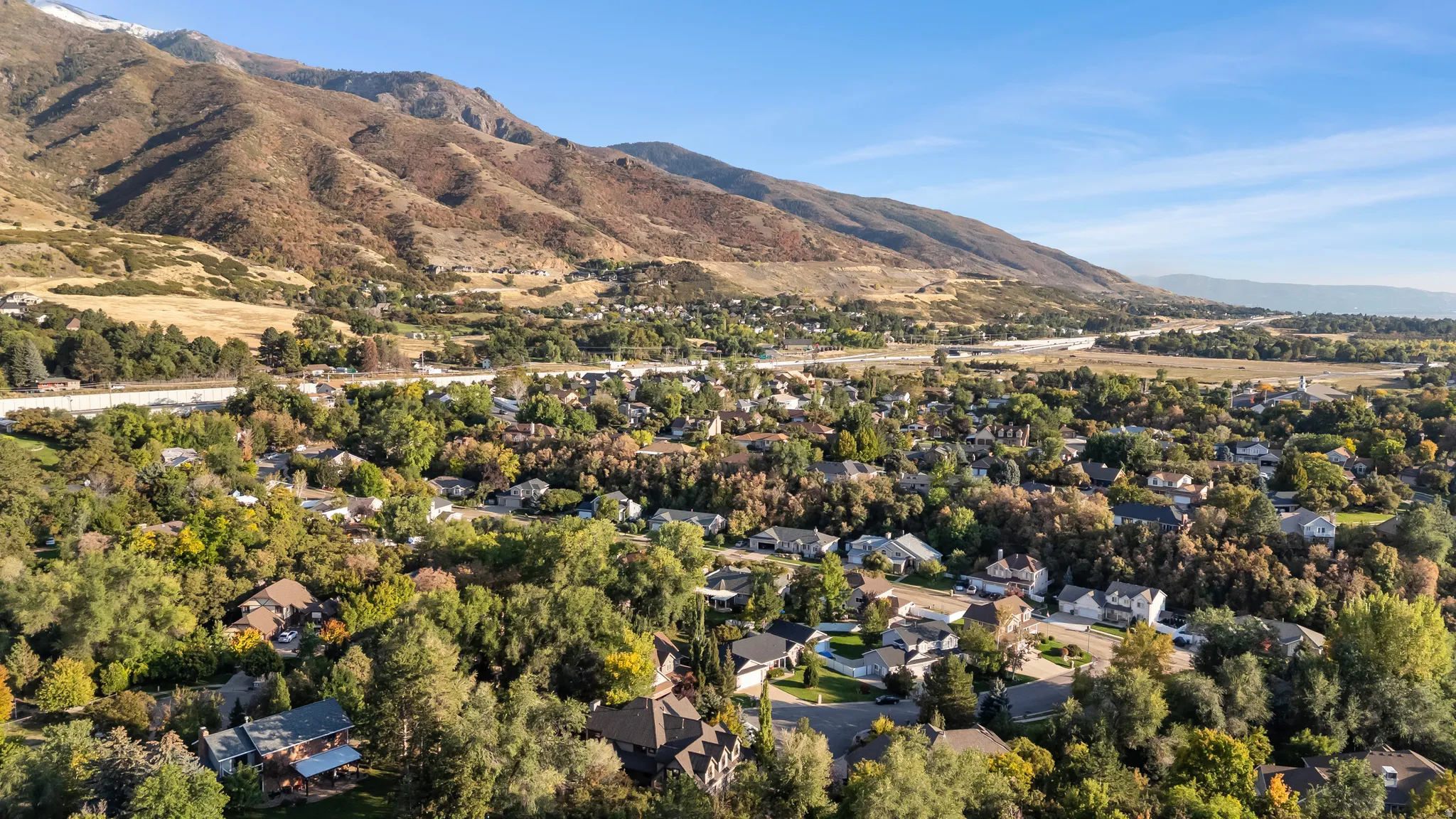 Expansive residential area featuring established homes, mature trees, and mountainous terrain