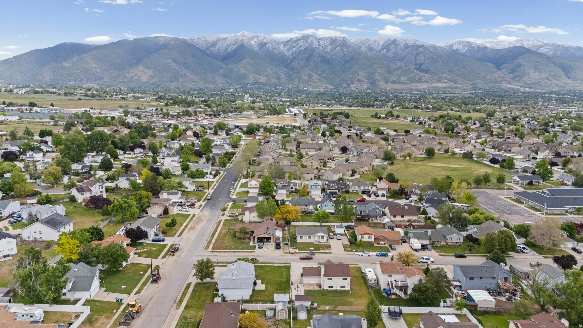 Expansive neighborhood with diverse residential architecture and mature trees, featuring a prominent mountain range backdrop
