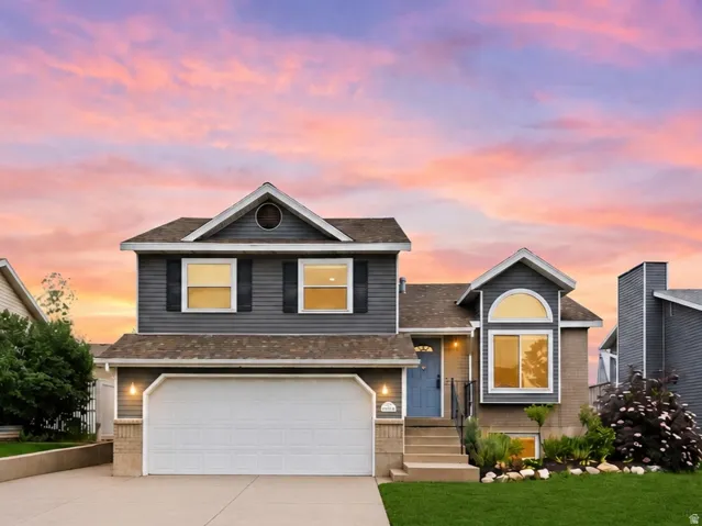 Two-story residence featuring grey siding, a two-car garage, and a manicured lawn