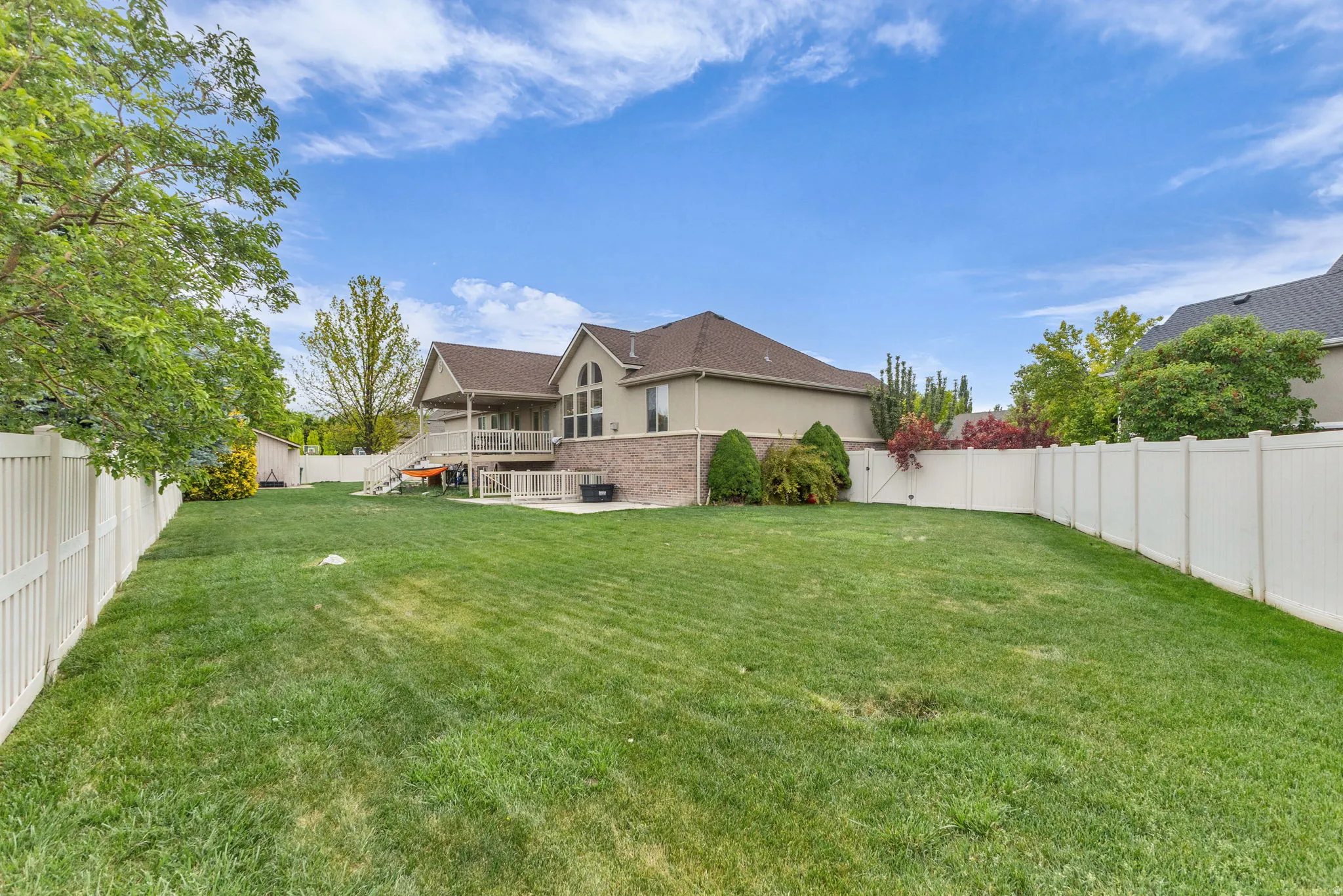 Expansive green lawn framed by a white privacy fence