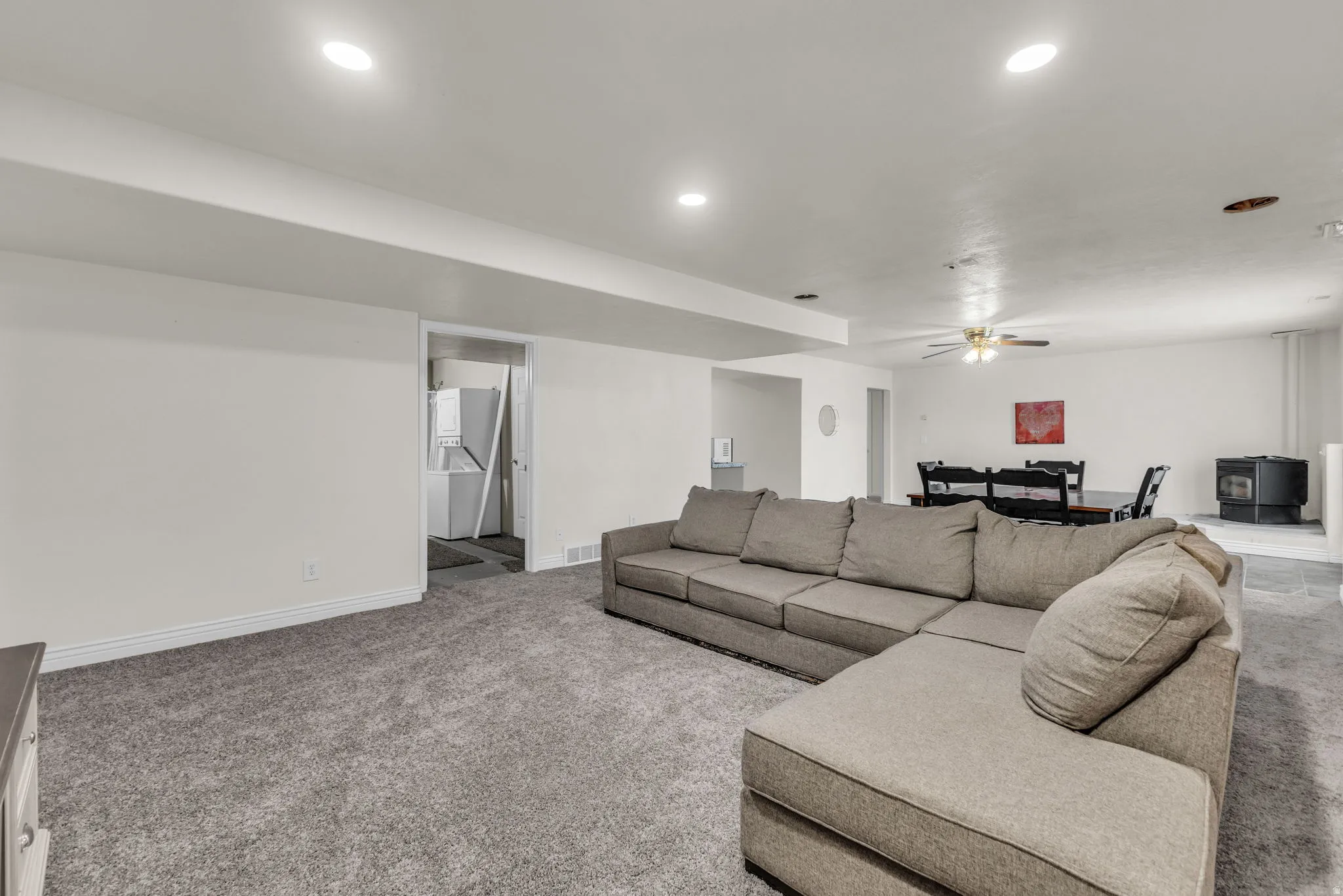Spacious lower-level area with recessed lighting and neutral gray carpeting throughout