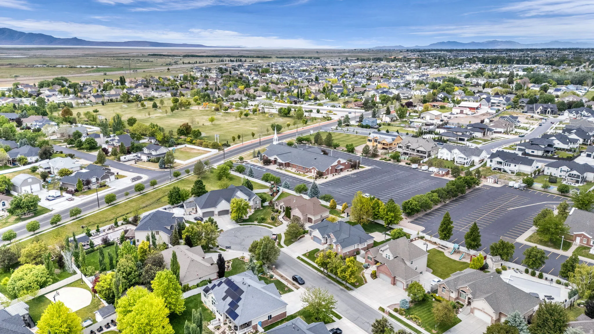 Expansive aerial view showcasing a residential community with varied architectural styles, mature landscaping, and an organized street grid