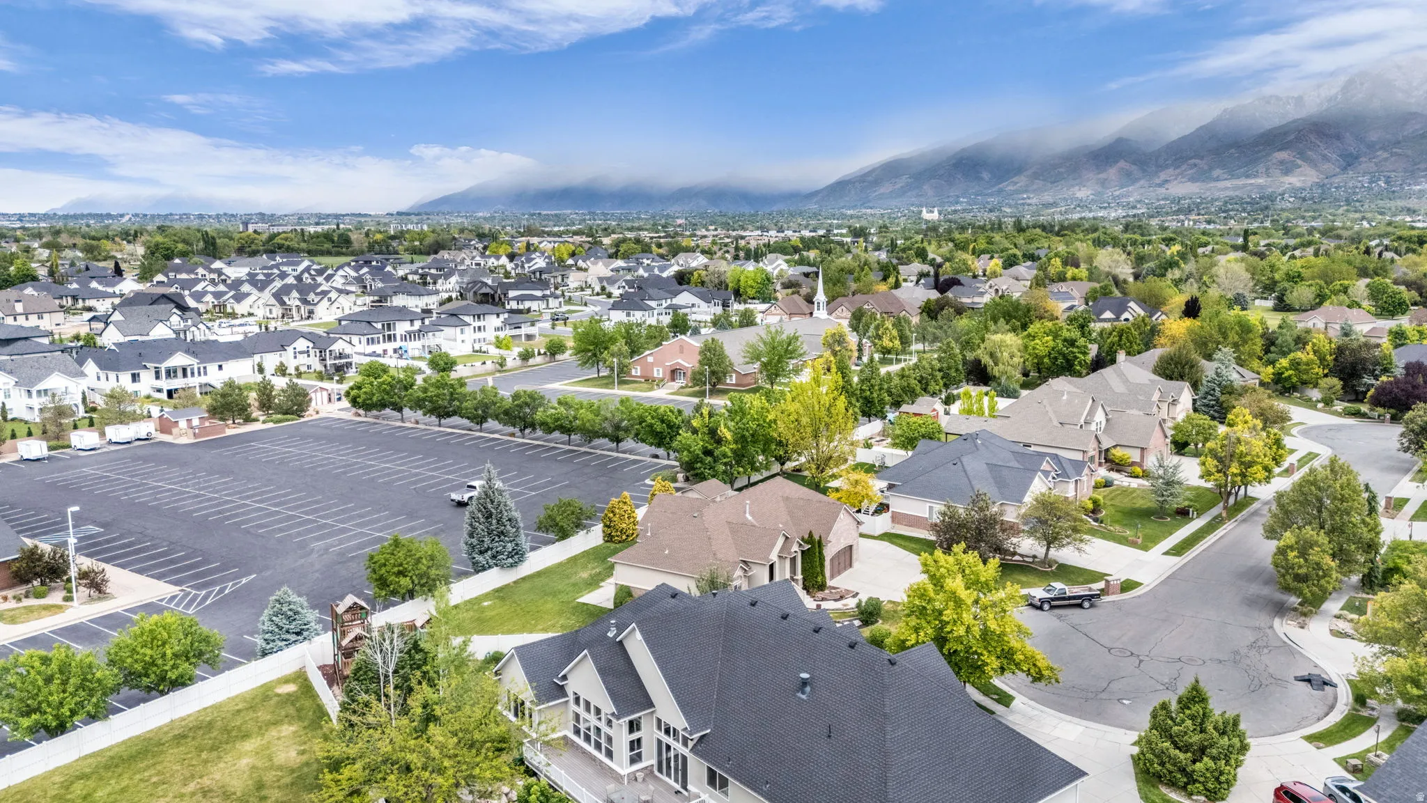 Residential neighborhood with mature trees, established homes, and mountain scenery