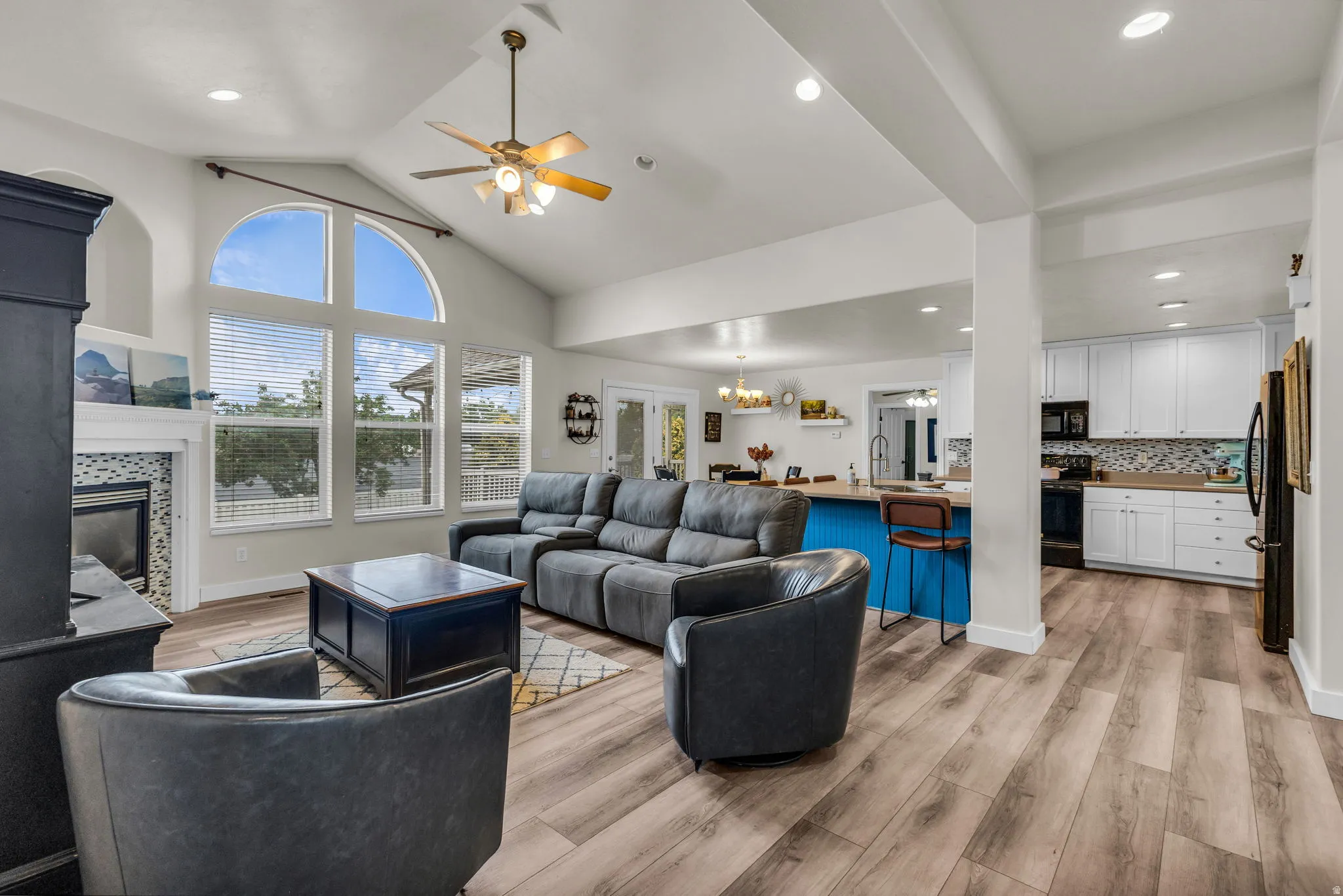 Vaulted ceilings with a ceiling fan and recessed lighting illuminate this open-concept living area