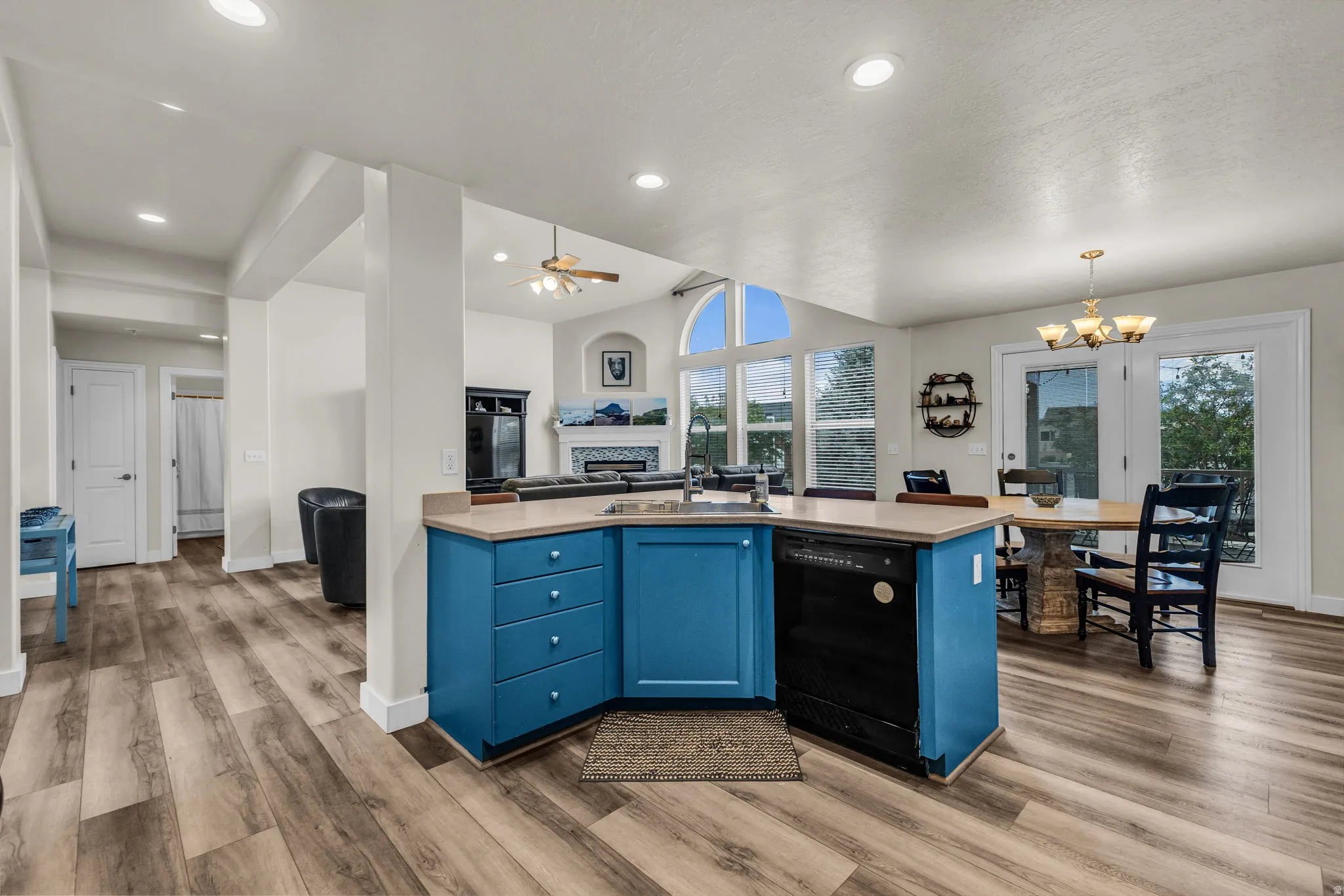 Kitchen island with blue cabinetry, a built-in sink, and dishwasher, complemented by wood-finish flooring