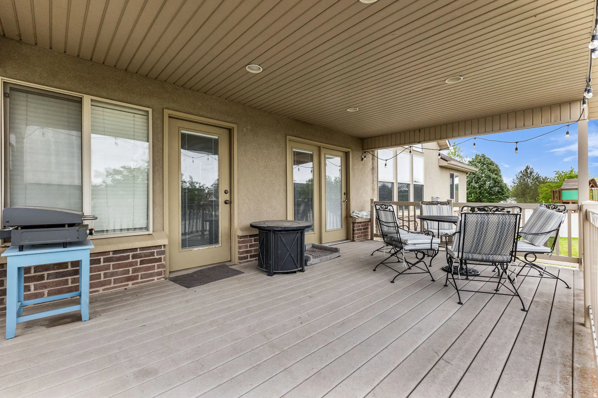 Spacious covered deck featuring composite decking, recessed lighting, and dual glass-paned doors