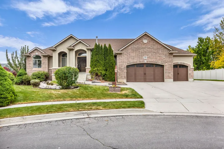 Traditional-style home featuring a brick and stucco exterior, arched window details, and a concrete driveway