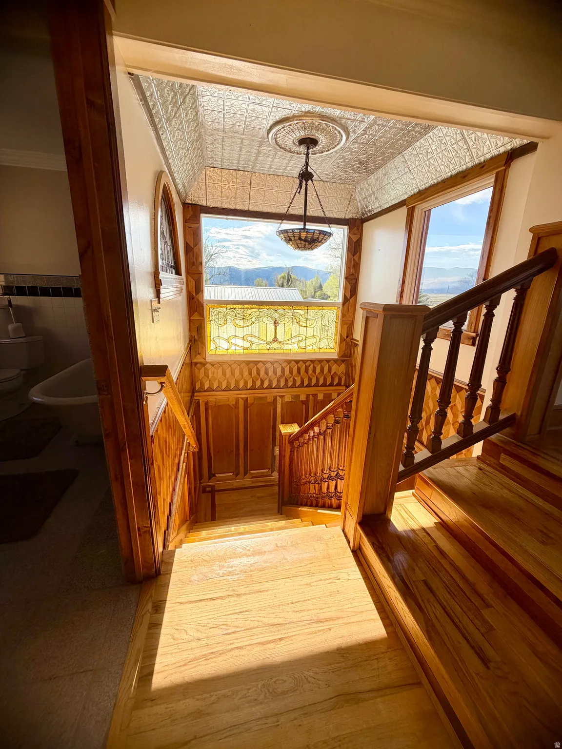 Wood-paneled staircase featuring an ornate balustrade and wood-finish flooring
