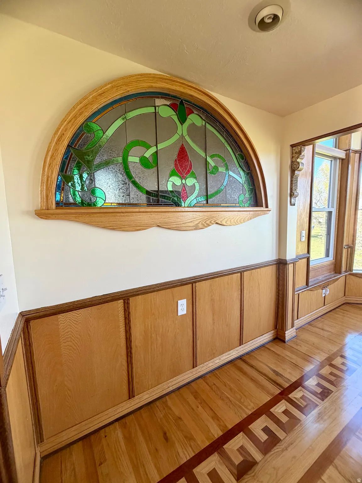 Arched stained glass transom window featuring intricate floral designs