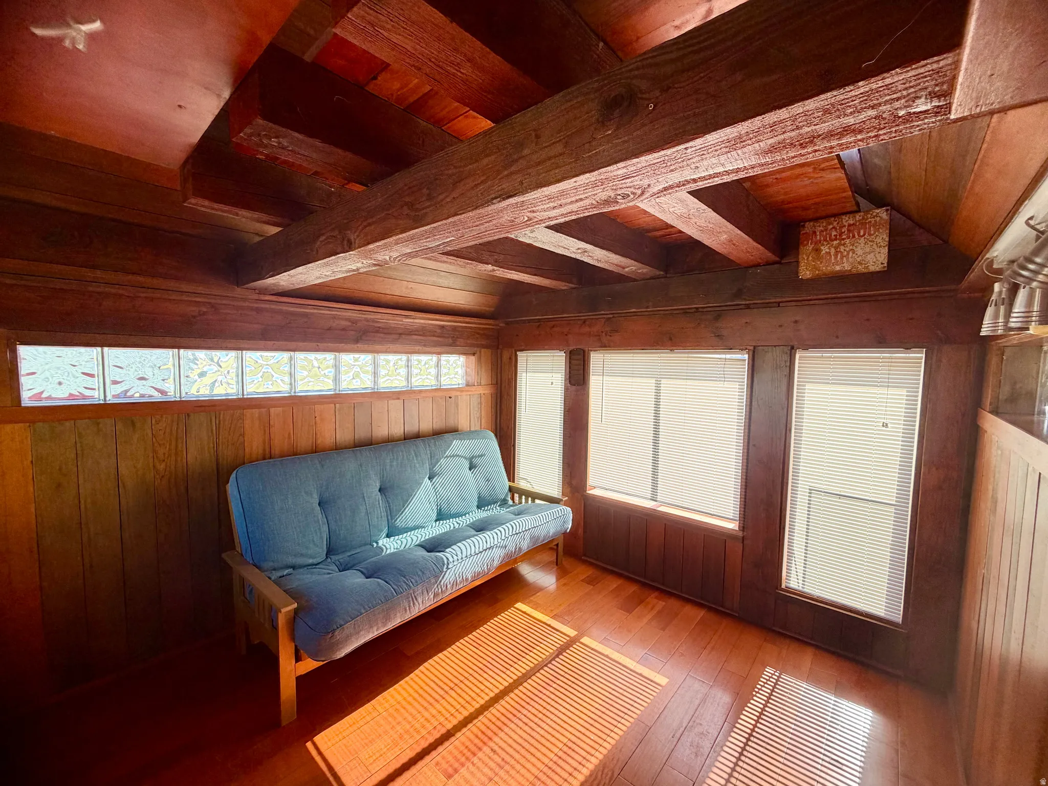 Wood-paneled room featuring exposed ceiling beams and wood-finish flooring