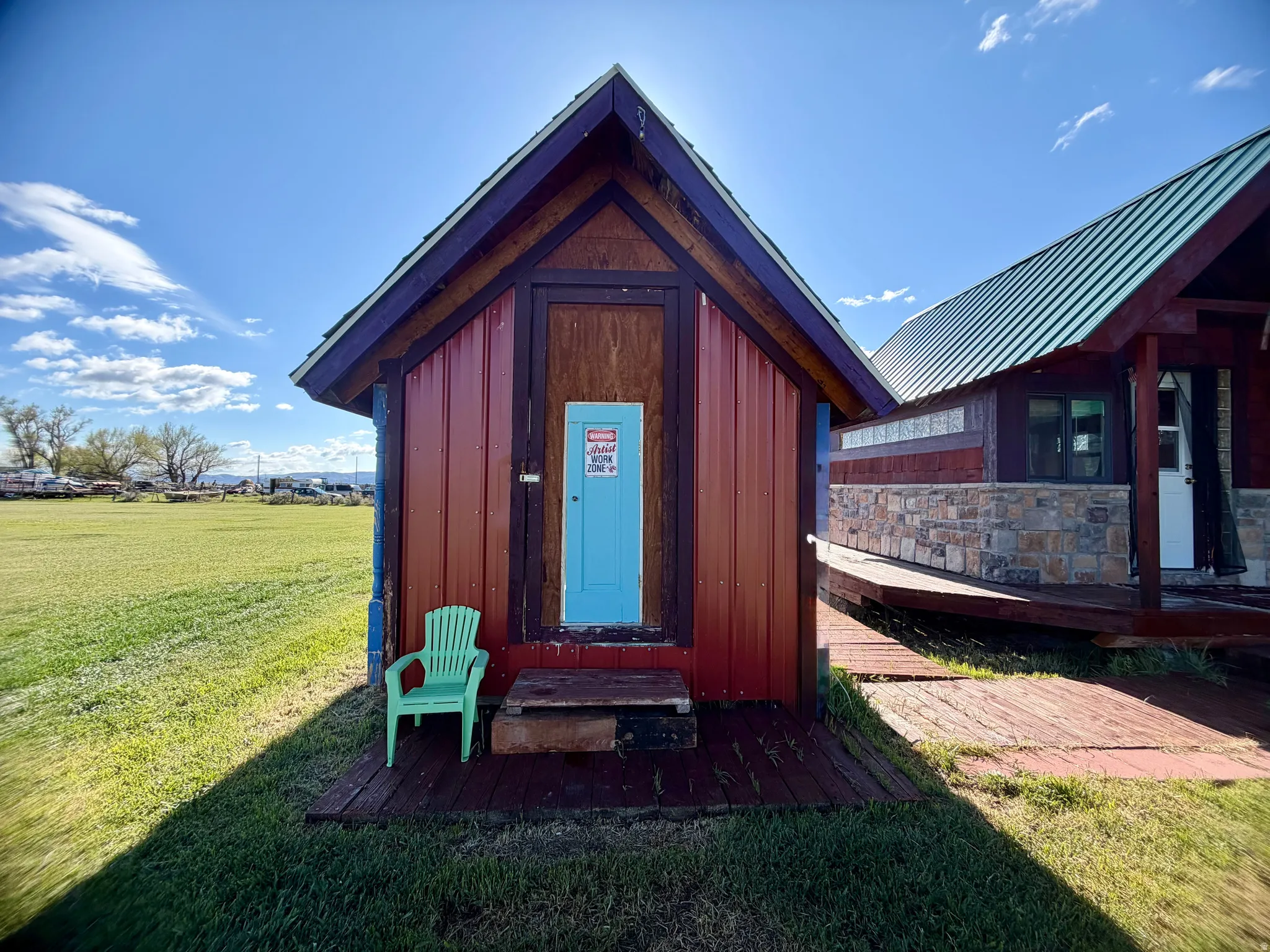 Compact outdoor structure with red corrugated siding and a bright blue door