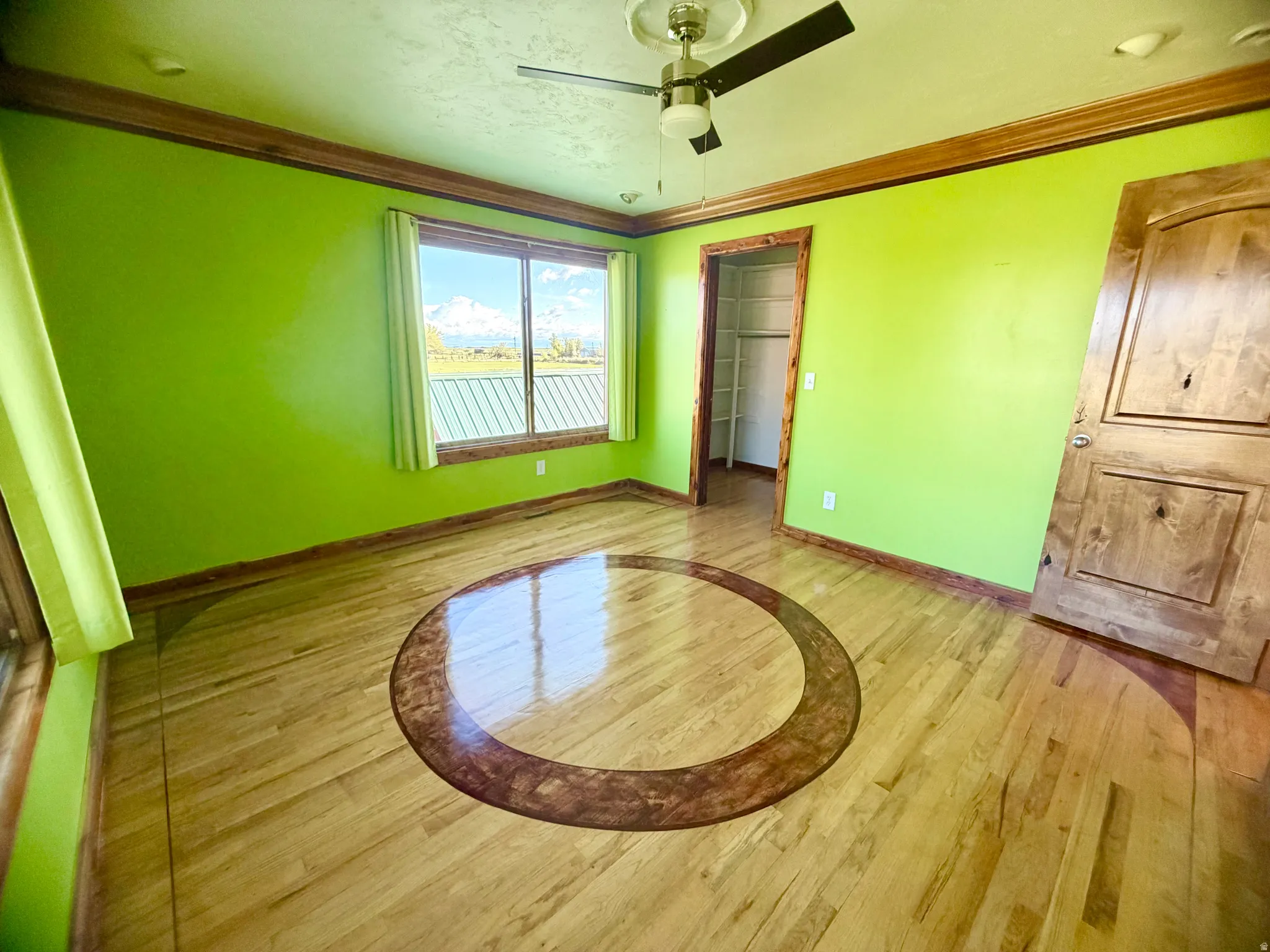 Room featuring wood-finish flooring with an inlaid circular design, a window offering mountain scenery, a ceiling fan, and a built-in closet with shelving