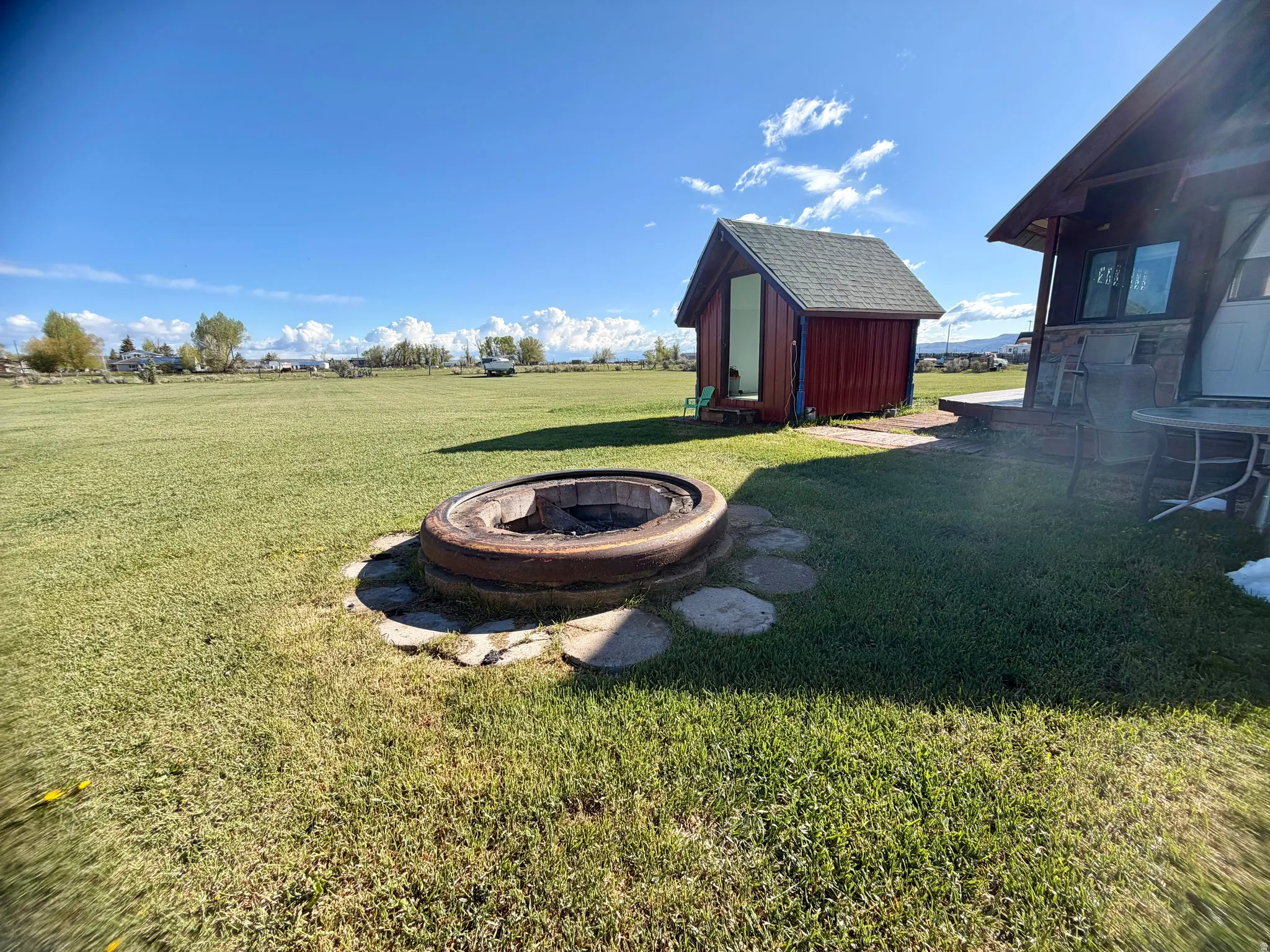 Expansive green lawn with a built-in fire pit featuring stone paver accents