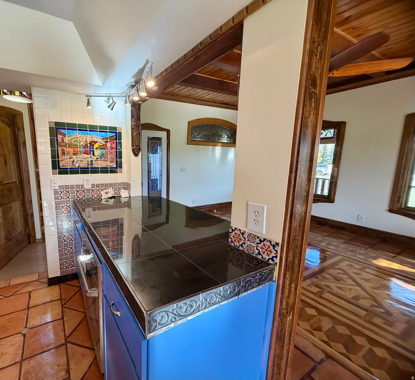 Kitchen island featuring a tiled countertop, vibrant blue cabinetry, and decorative tile detailing