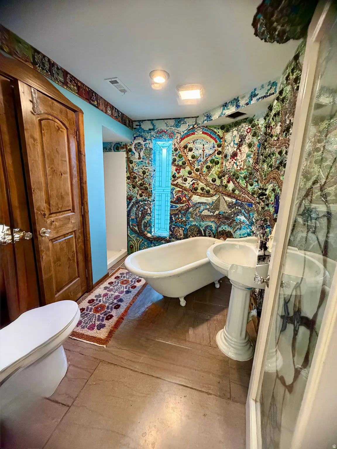 Bathroom featuring full mosaic wall art, clawfoot tub, pedestal sink, and wood-finish flooring