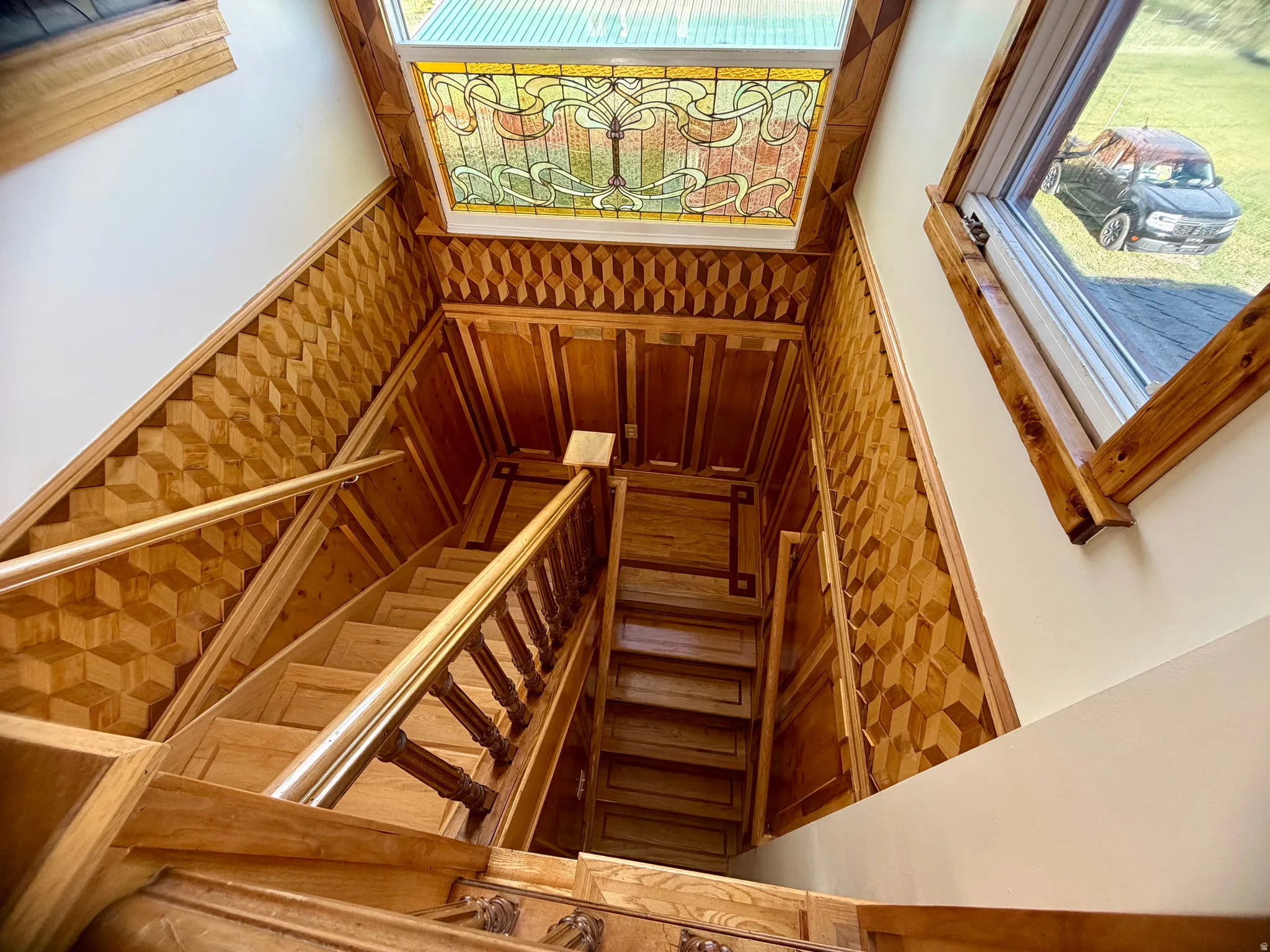 Grand wooden staircase featuring custom wood paneling with an intricate geometric pattern