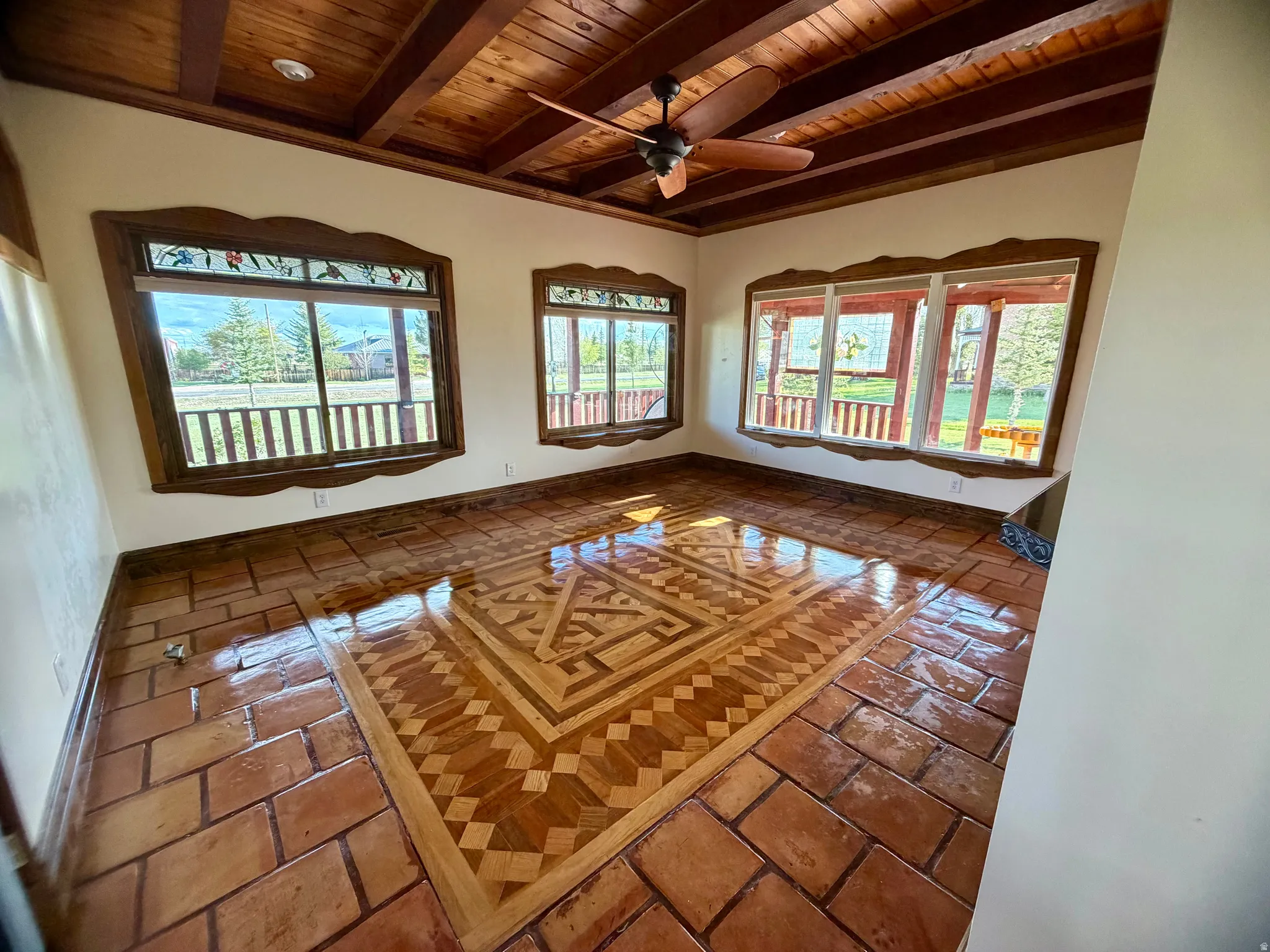 Room featuring a patterned wood-finish floor inlay surrounded by terracotta tile