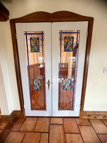 Double doors featuring leaded glass panels with colorful bird and floral motifs