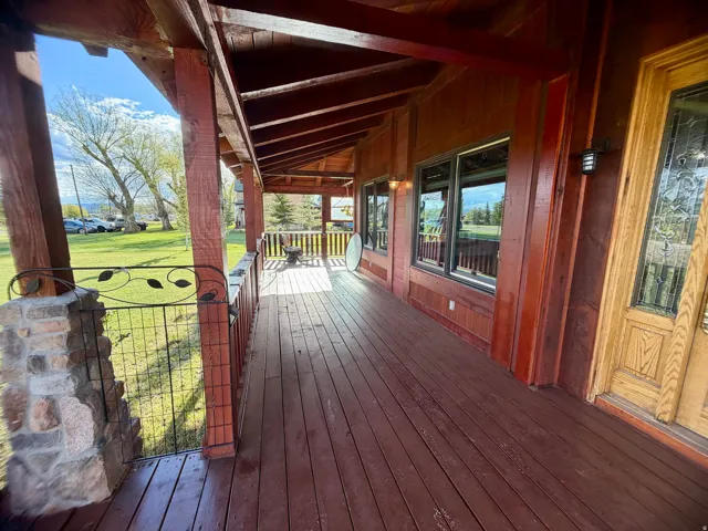 Expansive covered porch featuring wood-finish flooring, exposed beam ceiling, wood-paneled exterior walls, and multiple windows