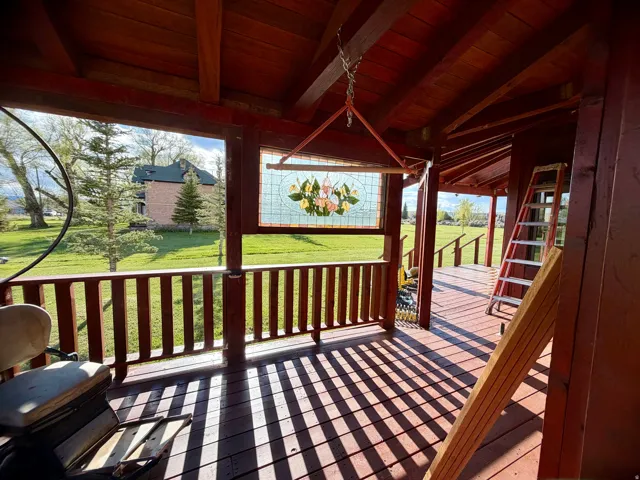 Covered porch featuring a stained-glass window, wood plank flooring, and a railing system