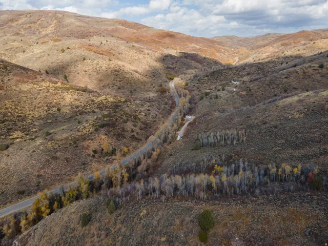 Expansive mountain landscape featuring a winding road, natural terrain, and scattered trees