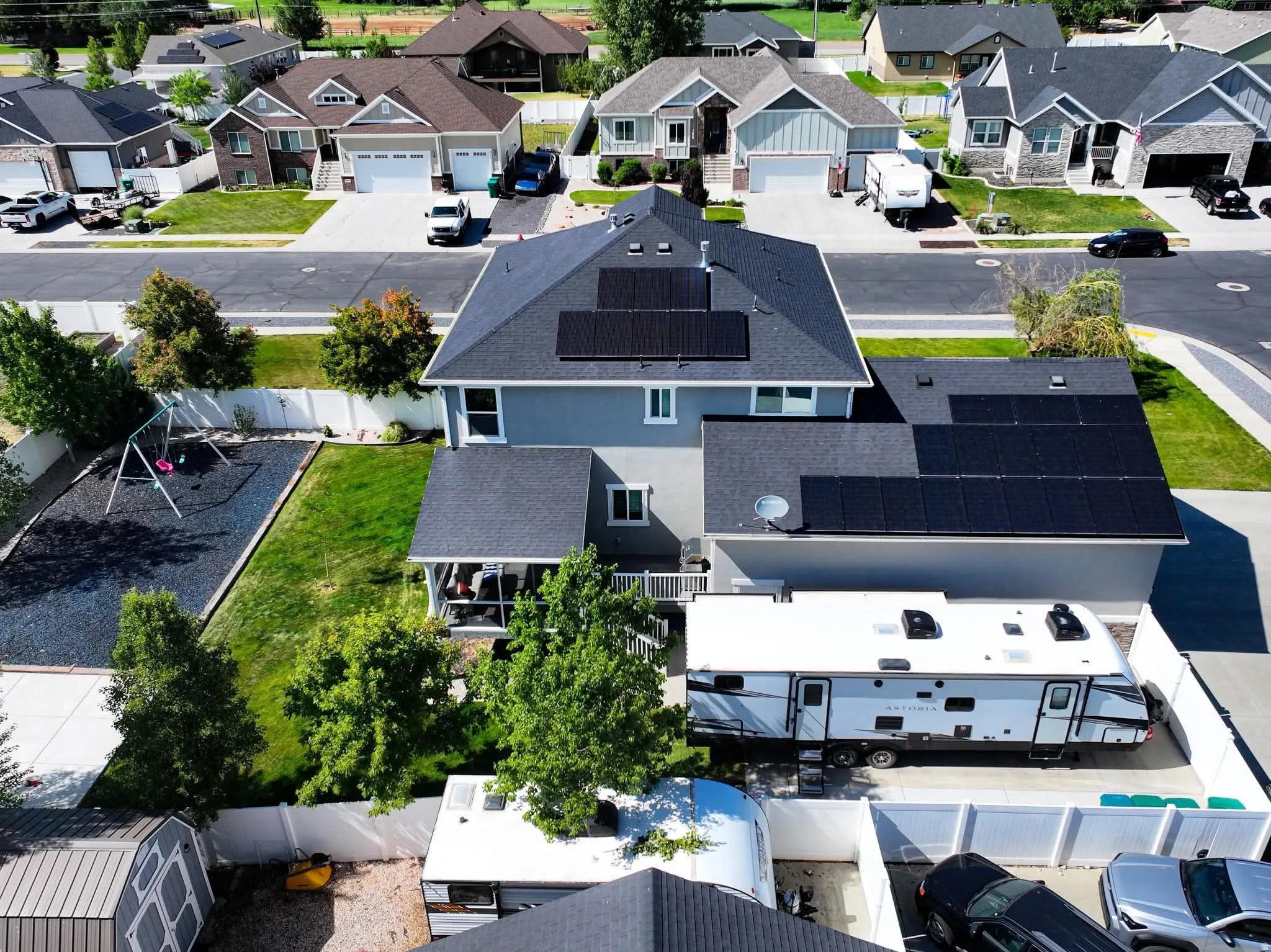 Gray two-story residence featuring a dark shingled roof with integrated solar panels