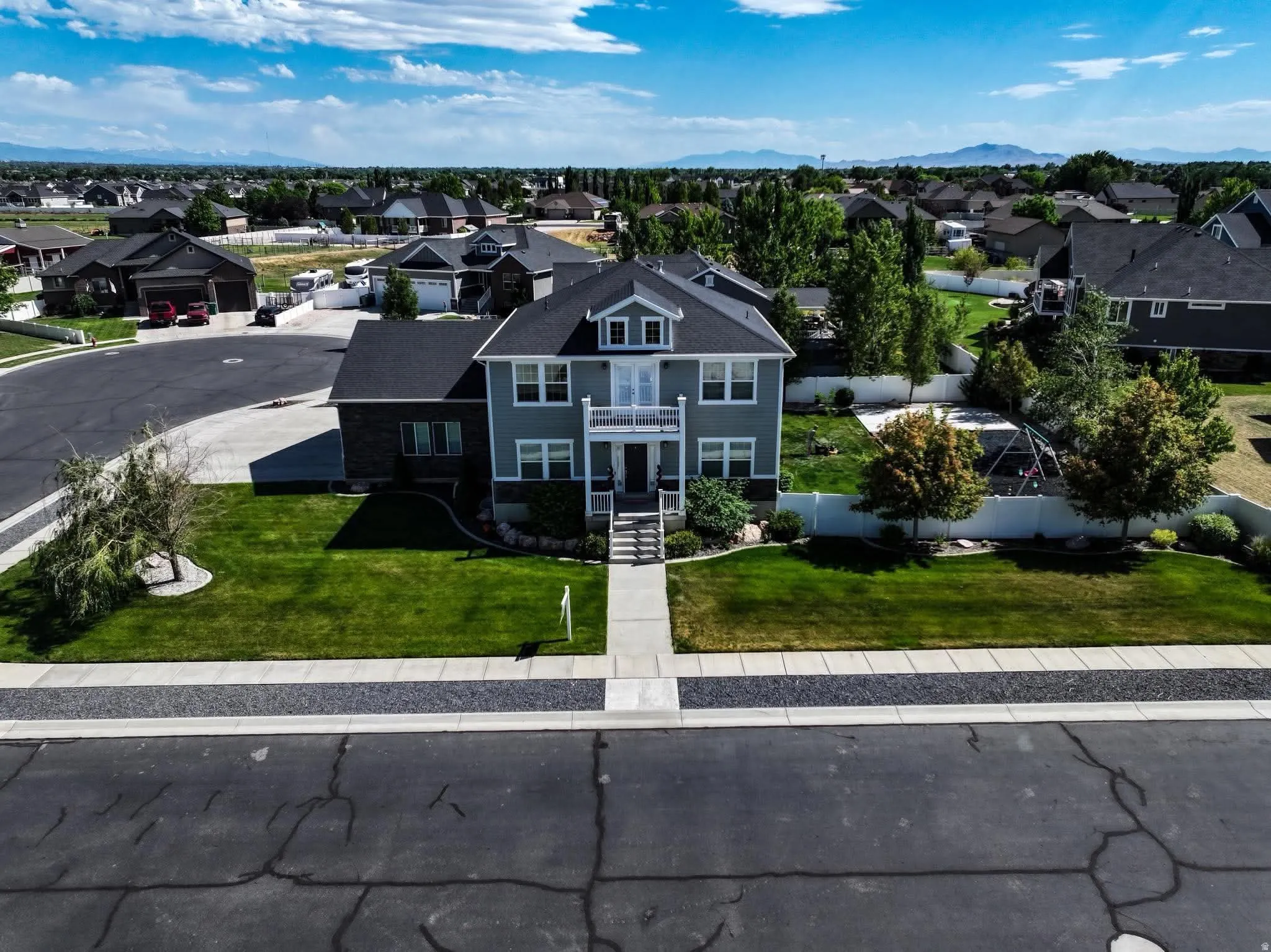 Two-story residential property with a gray siding and dark roof, set on a manicured lawn