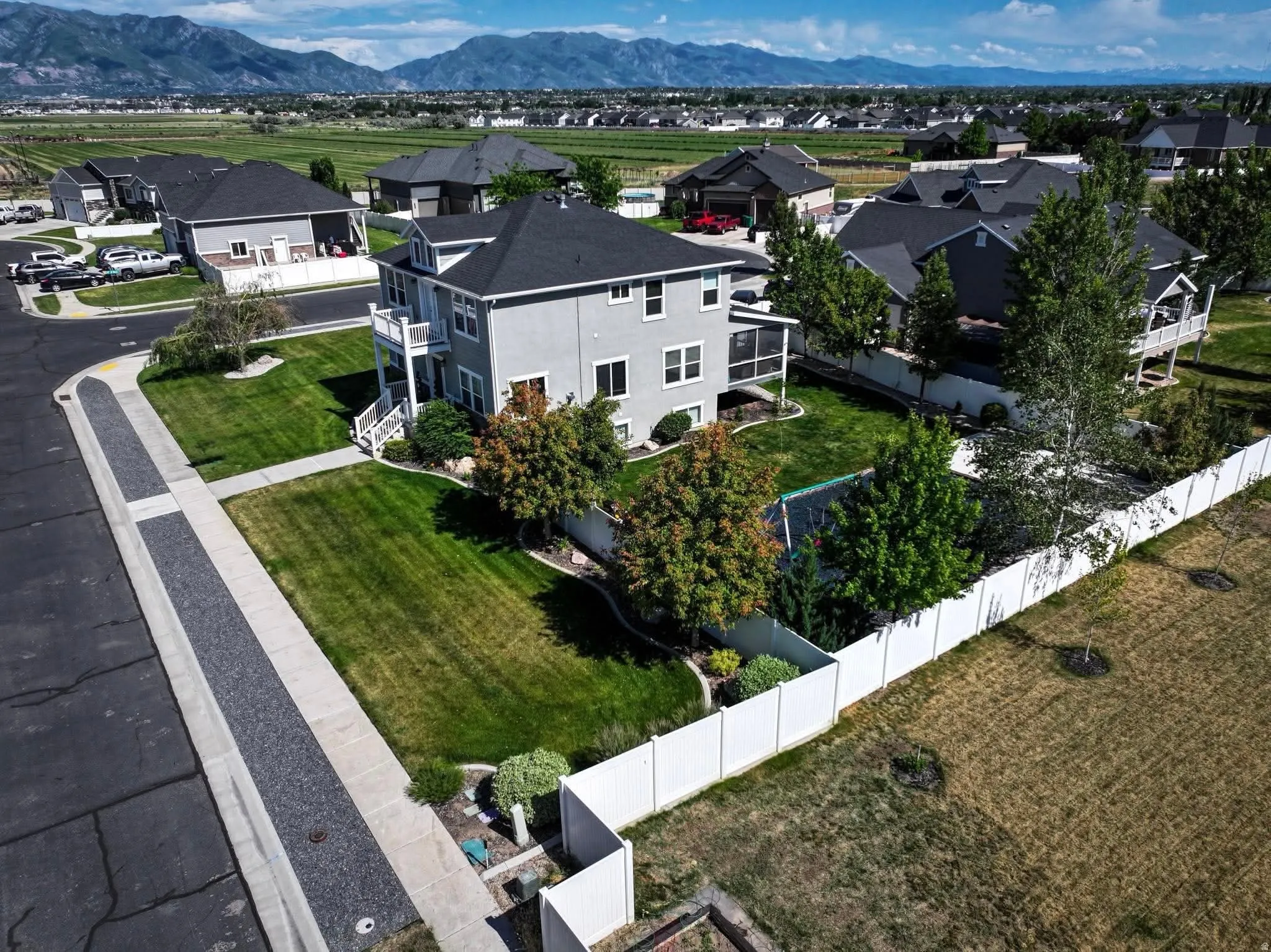 Two-story residence with a light gray exterior, dark shingle roof, and white trim