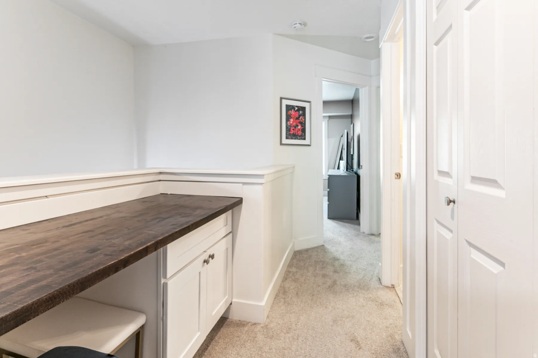 Built-in desk area featuring a dark wood-finish countertop and white cabinetry with silver hardware