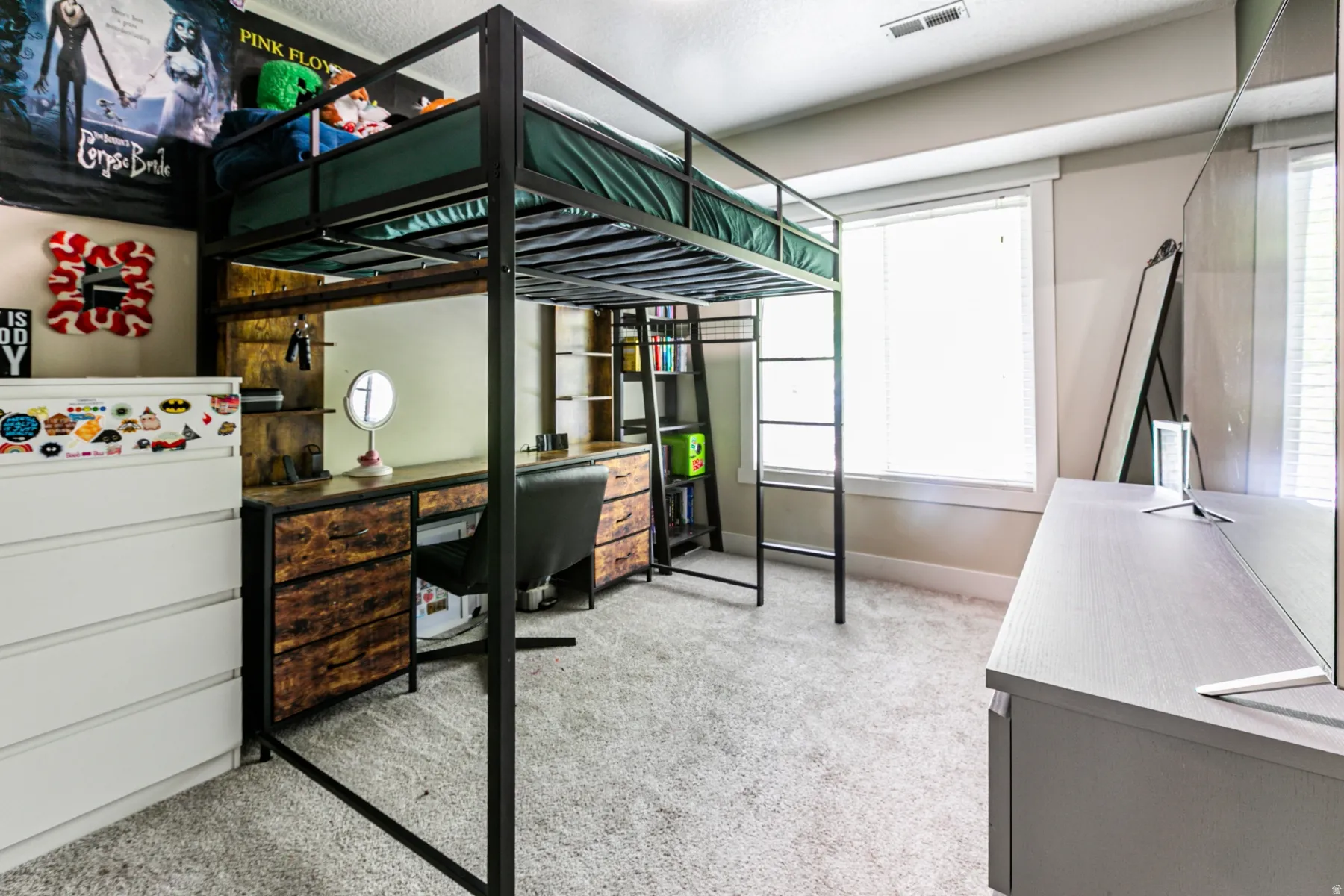 Carpeted bedroom three featuring a loft bed frame with integrated desk and shelving, a white five-drawer dresser, and a large window with blinds