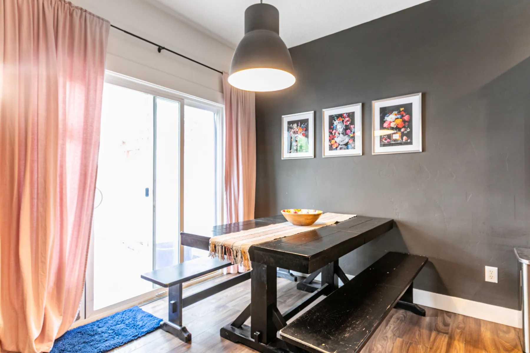 Sliding glass doors providing outdoor access, wood-finish flooring, and a dark gray accent wall