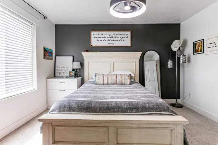 Contemporary primary bedroom featuring a dark accent wall, recessed lighting, and a window with blinds