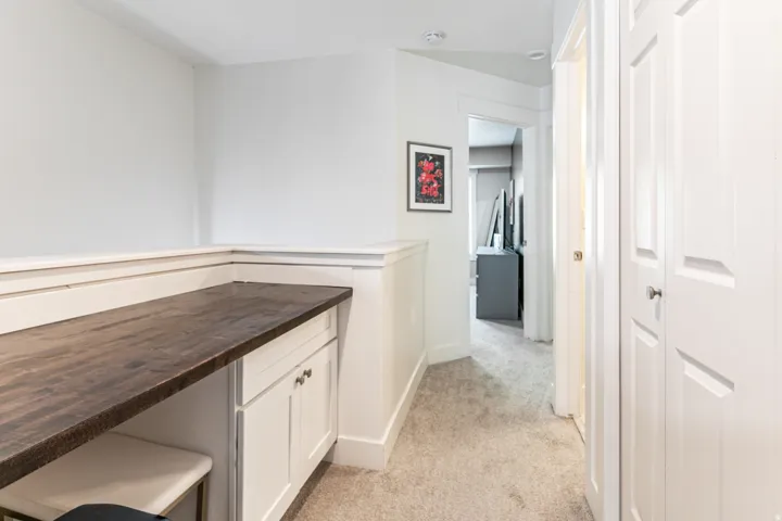 Built-in desk area featuring a dark wood-finish countertop and white cabinetry with silver hardware