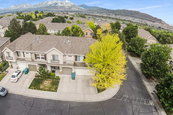 Townhome exterior featuring a neutral stucco and siding facade, individual garage access, and a prominent mountain backdrop