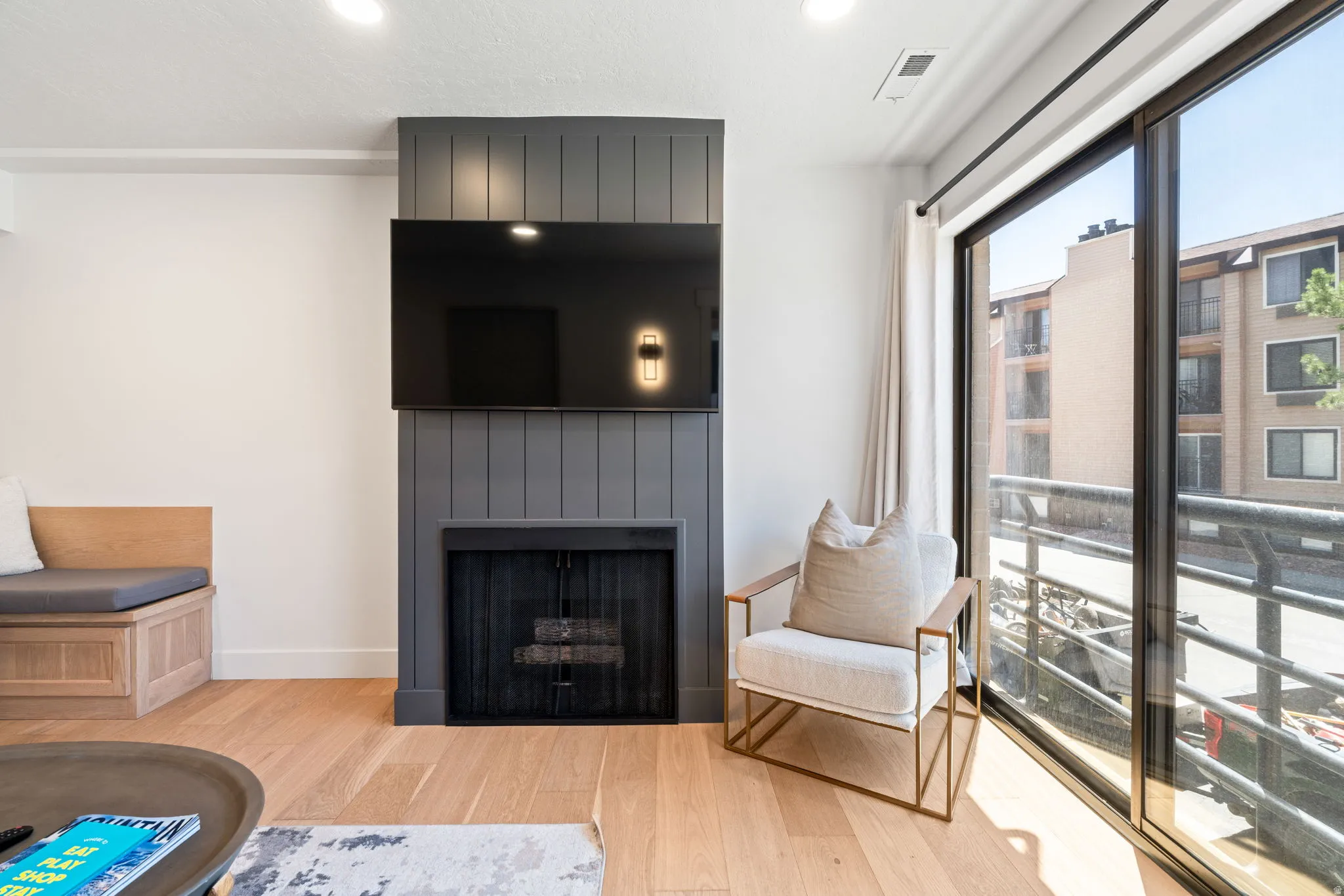 Living area featuring a floor-to-ceiling accent wall with a fireplace and sconce lighting