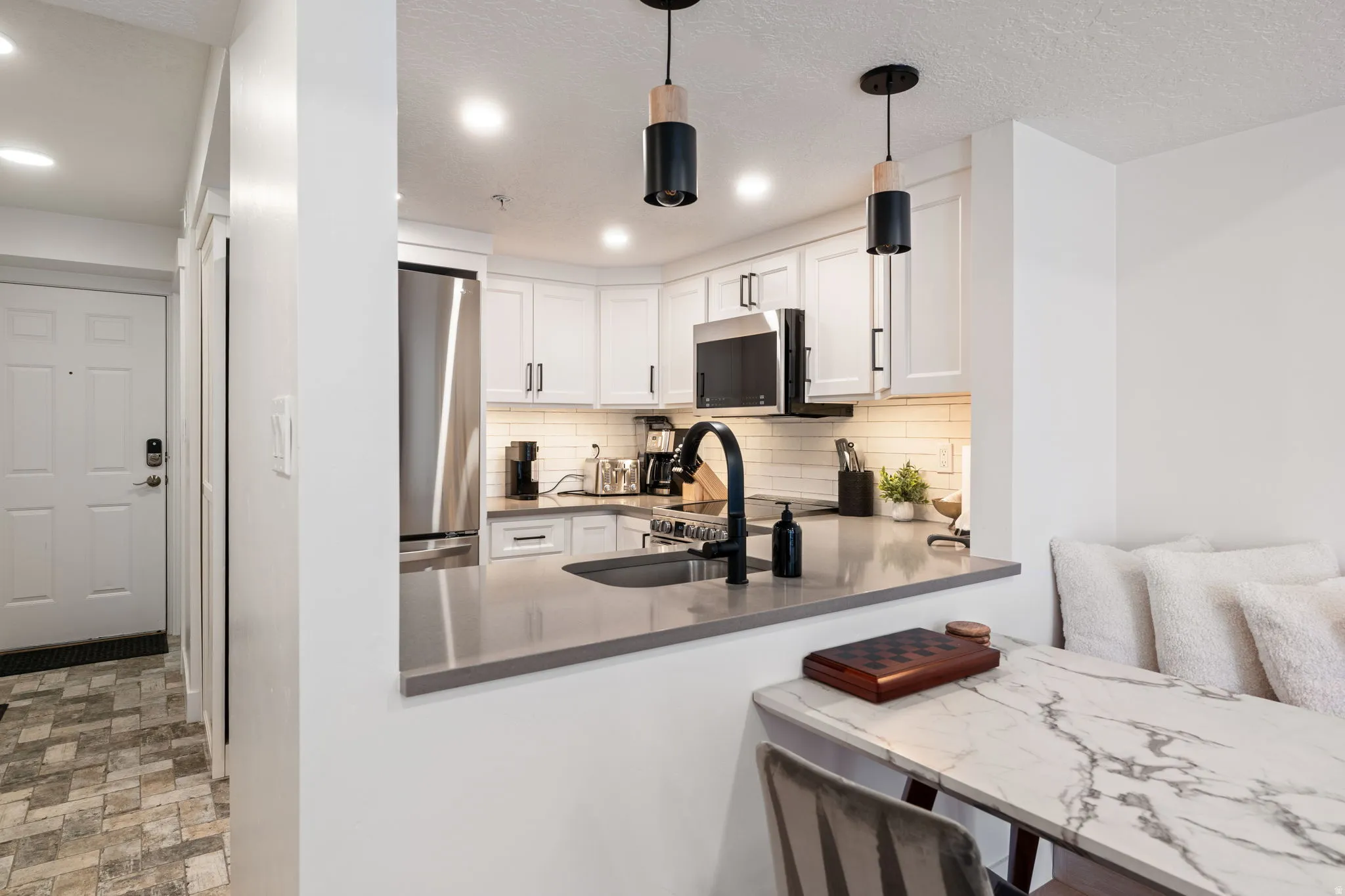 Contemporary kitchen featuring white shaker cabinetry, stainless steel appliances, and a grey countertop with an undermount sink