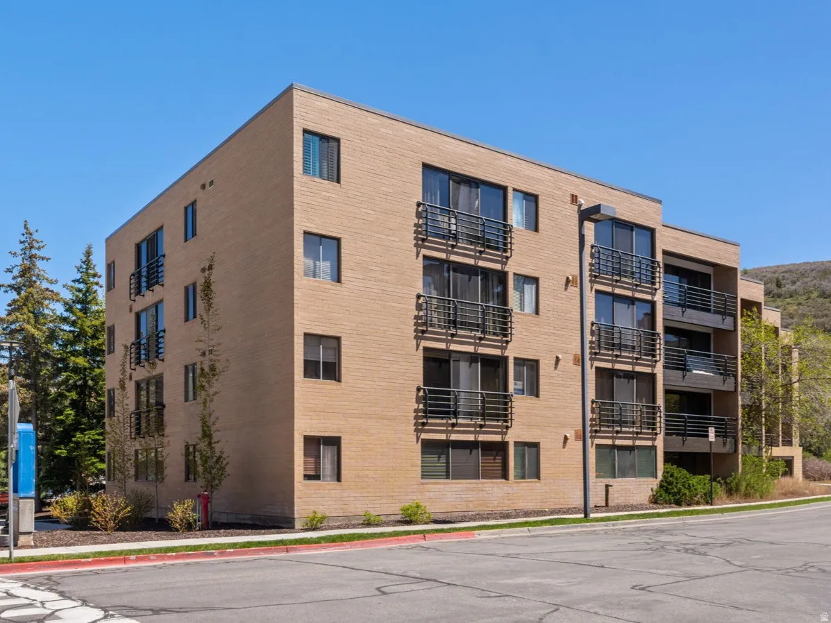 Multi-story building featuring a light brick facade and multiple private balconies with dark railings